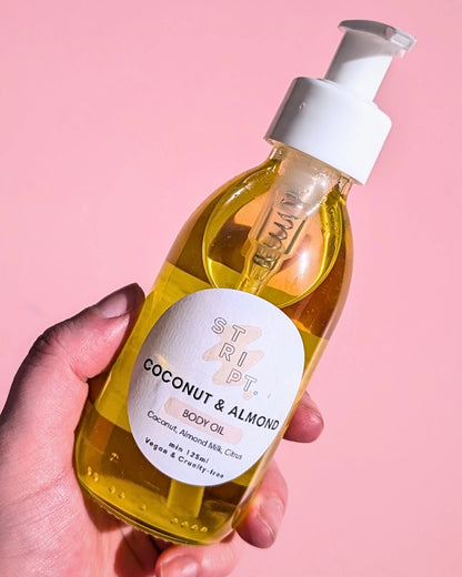 Coconut & Almond Body Oil by Stript Cosmetics | Handmade, Vegan Body Care | Hand holding a glass bottle with white label and white pump