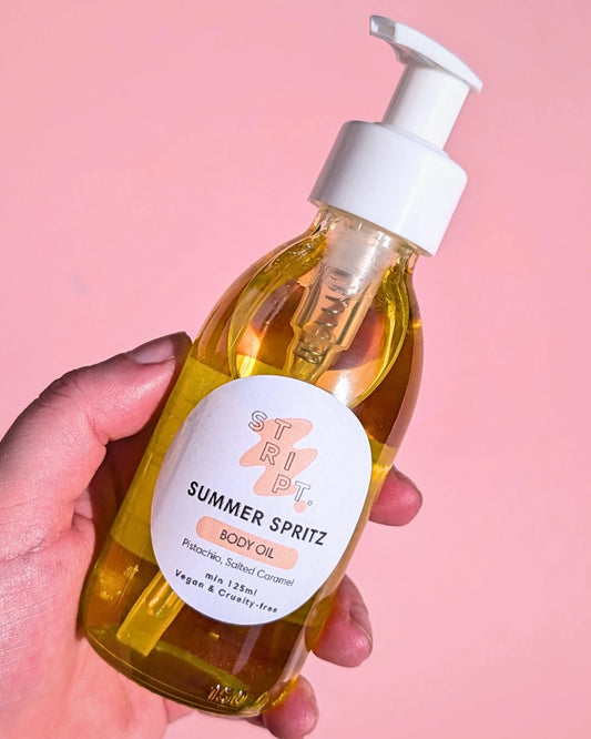 Summer Spritz Body Oil by Stript Cosmetics | Handmade, Vegan Body Care | Hand holding a bottle of 'Summer Spritz' body oil with a pink background